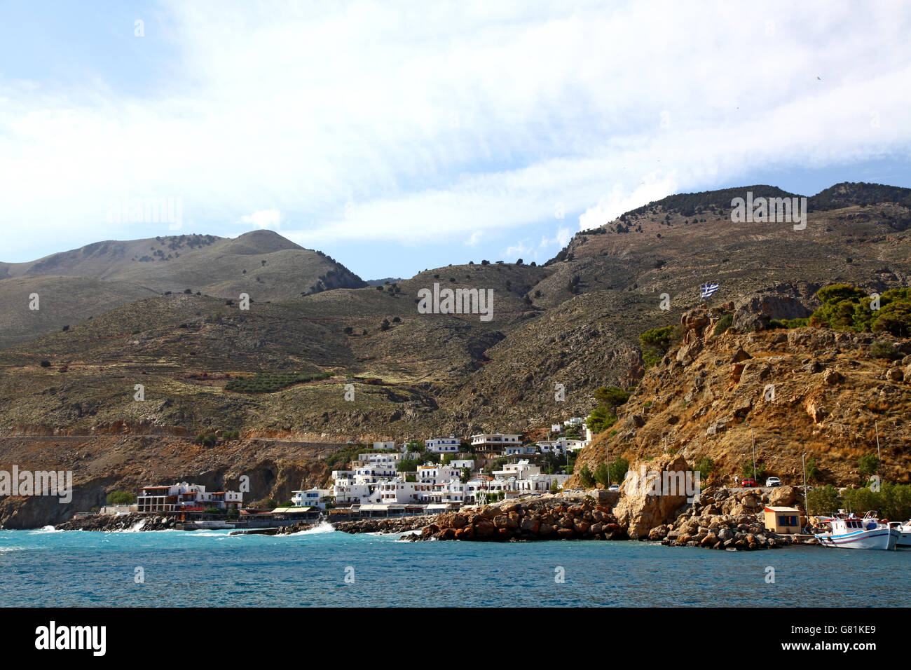 Una piccola pesca e porto turistico nel sud di Creta, visto dal mare con le sue case dipinte di bianco e le montagne alle spalle Foto Stock