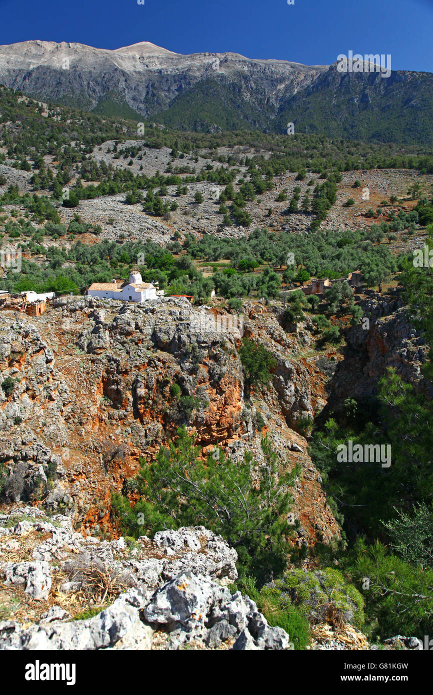 Un dipinto di bianco, tetto di tegole rosse e chiesa posatoi su una scogliera scoscese che si affaccia sulla gola di Aradena in una parte remota di Creta meridionale Foto Stock