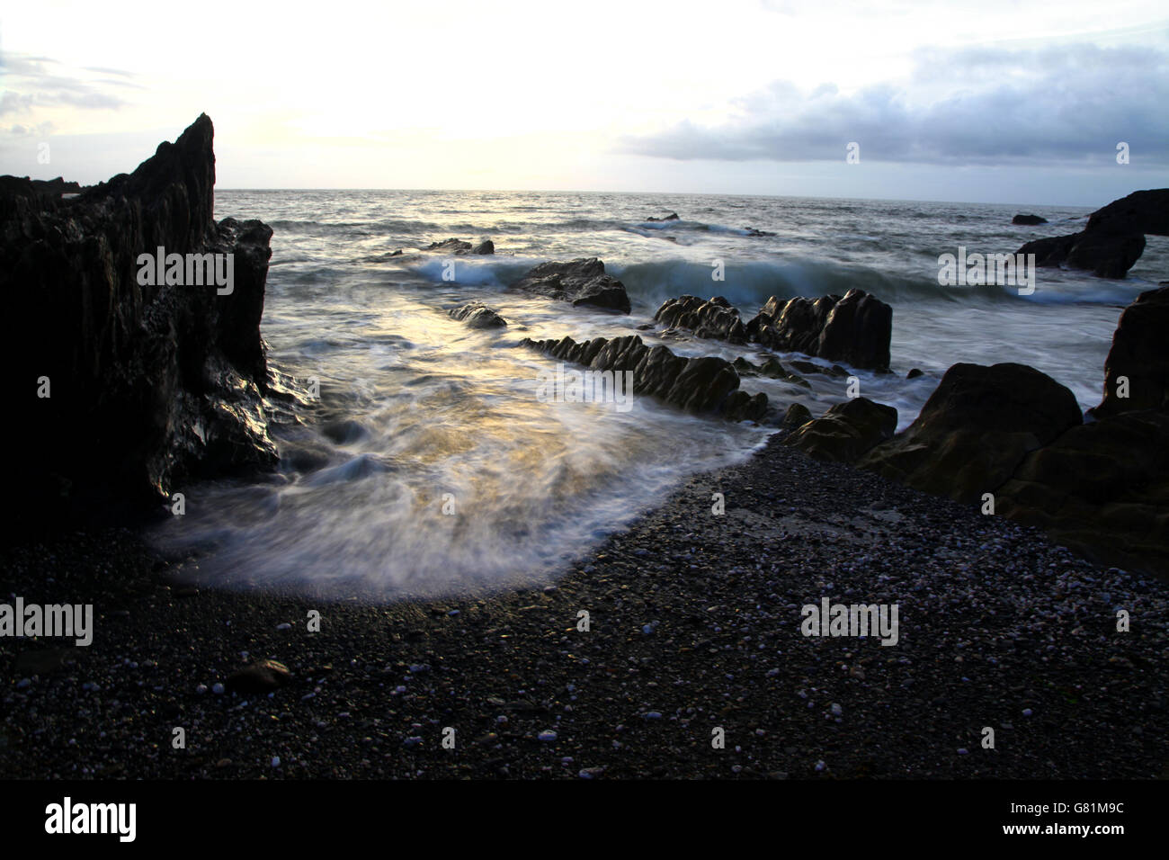 Stagliano rocce frastagliate su un litorale infiltrati con un oceano di schiumatura come onde curl in spiaggia Foto Stock