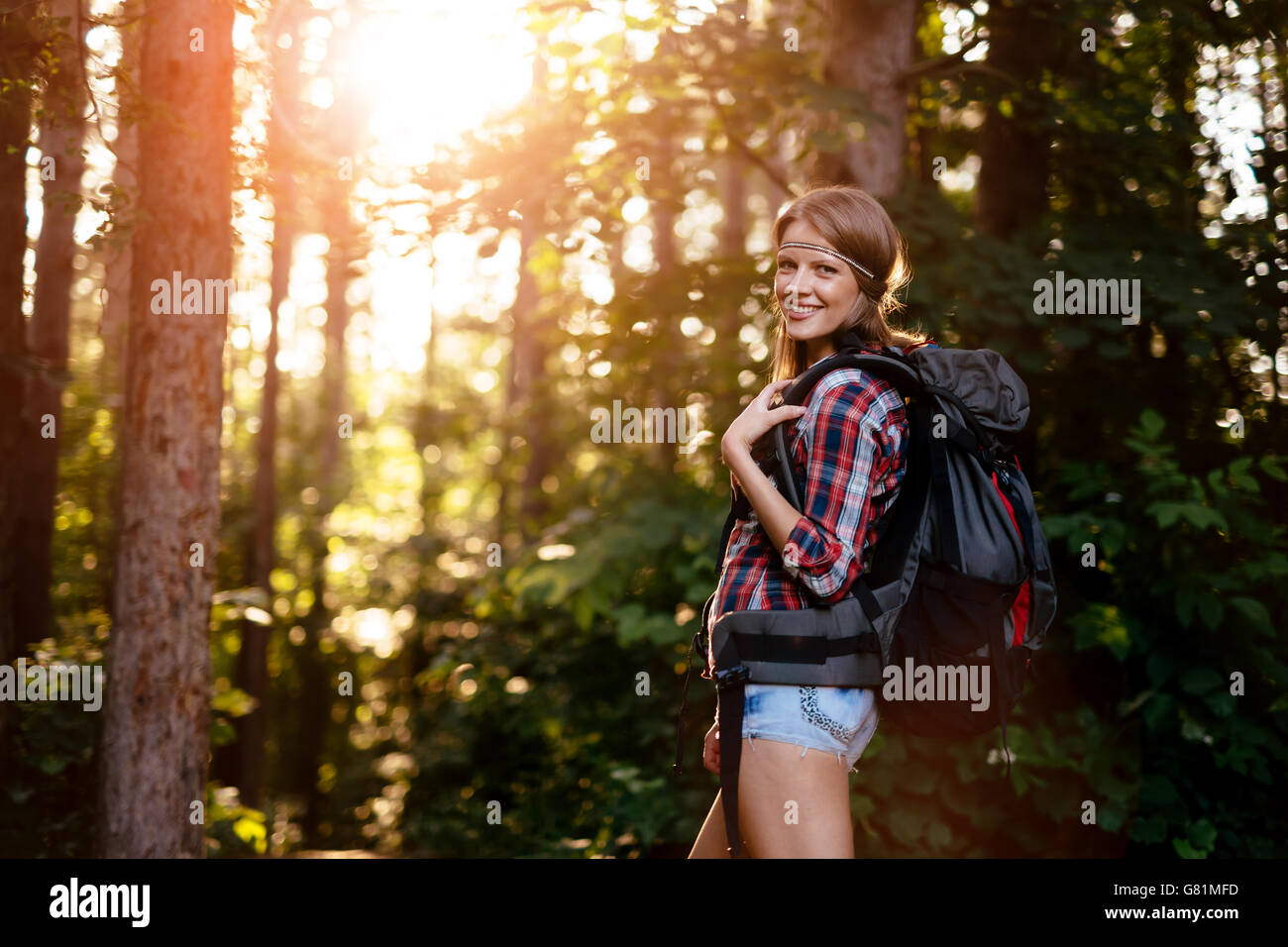 Bella donna trekking nella foresta che porta uno zaino Foto Stock
