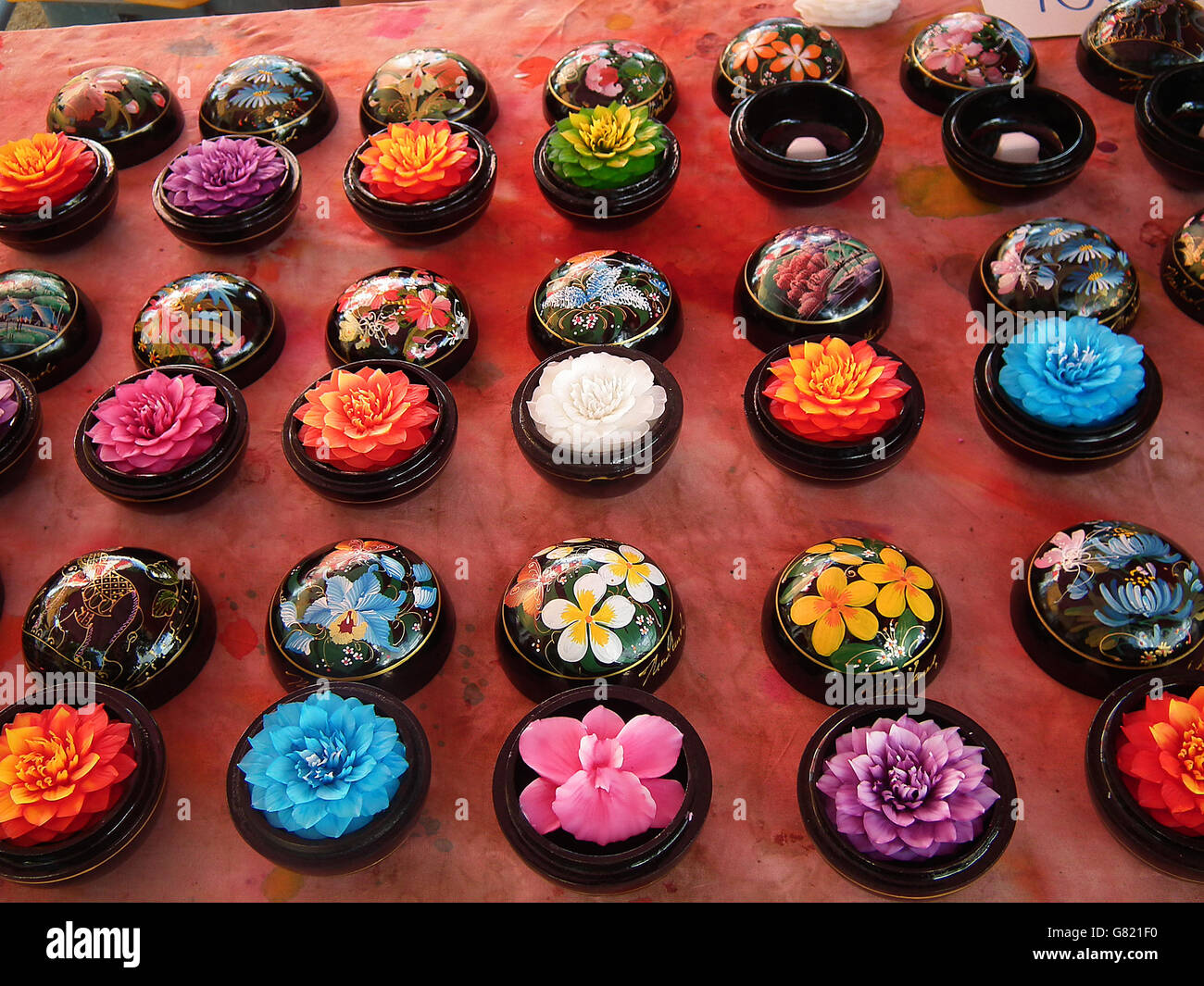 Diversi lotuses colorati in contenitori in ceramica sulla tabella rossa sul display, Bangkok, Thailandia, Novembre 2011 Foto Stock