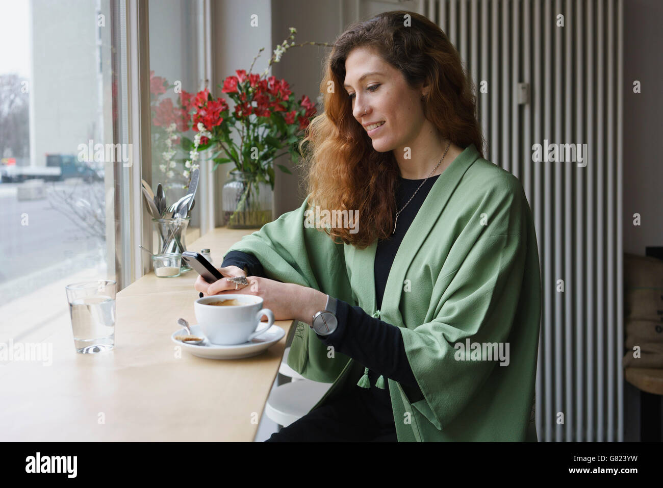 Giovane donna usando il telefono e un caffè al caffè Foto Stock
