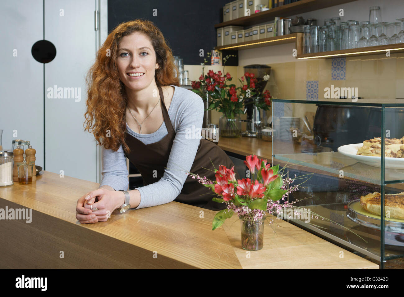 Ritratto di sorridente giovane donna in piedi dalla tabella al cafe Foto Stock