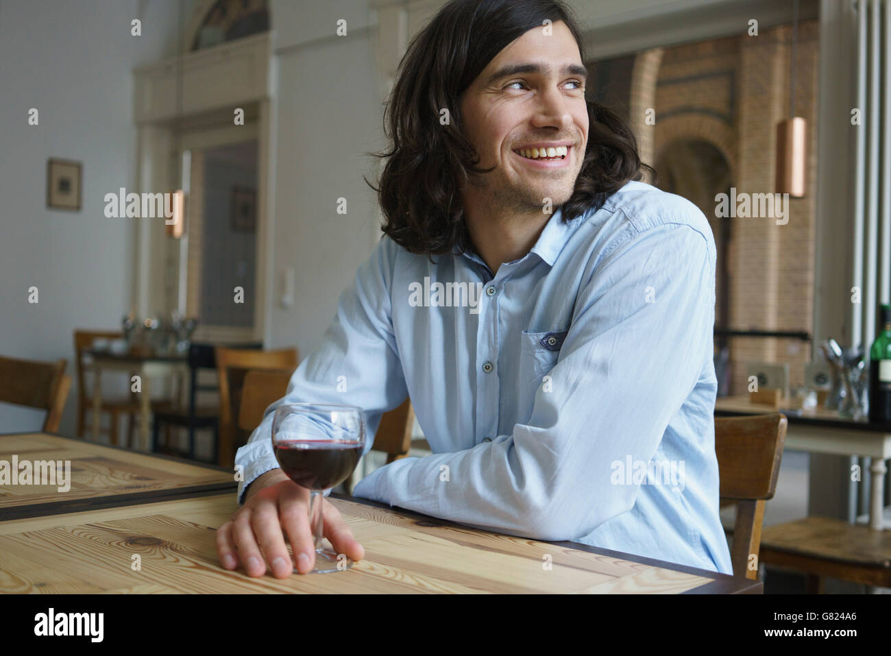 Uomo felice avente il vino seduti al caffè Foto Stock