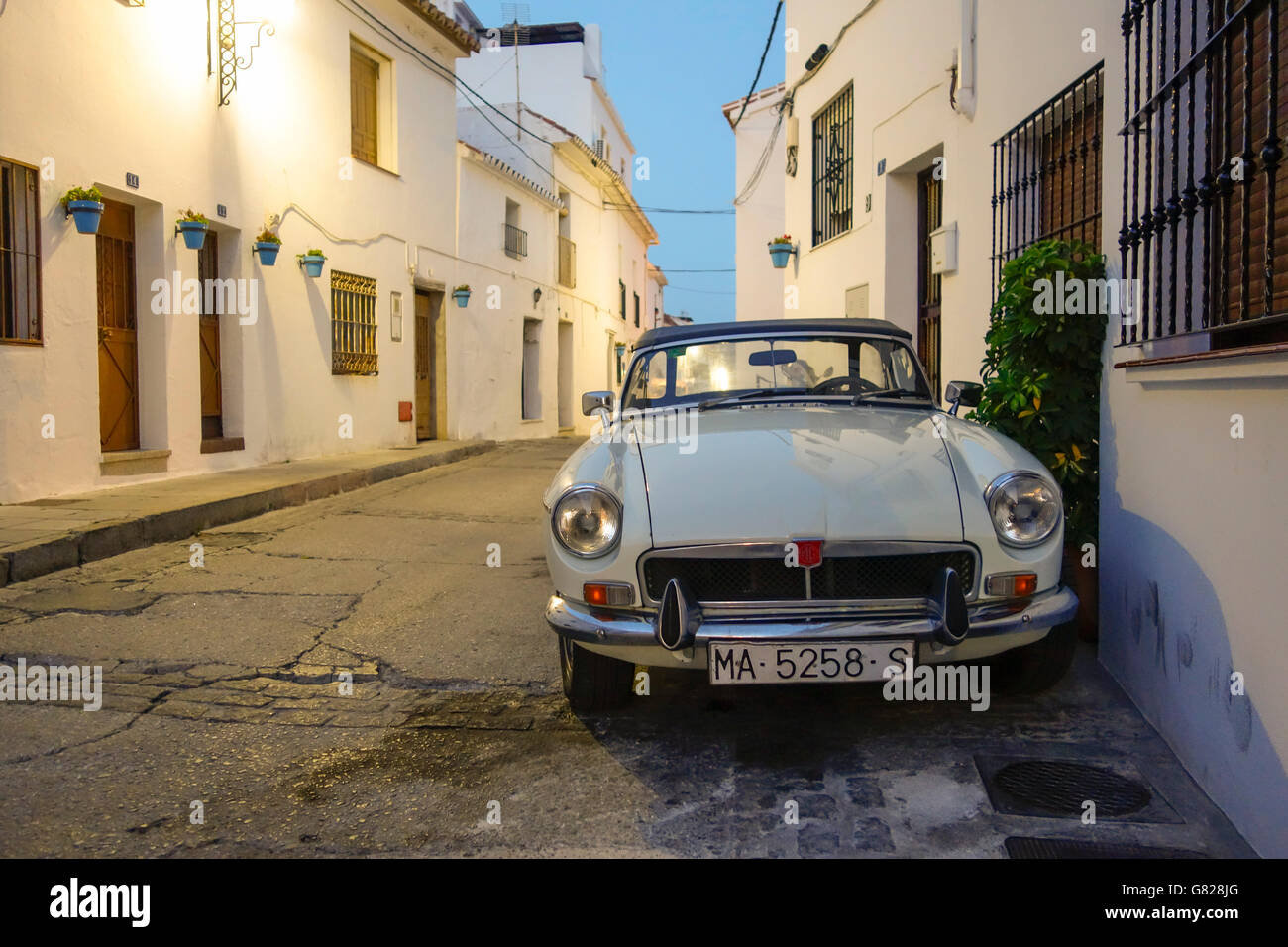 Vecchie MG B classic car, parcheggiata in strada in bianco al villaggio spagnolo. Mijas, serata. Spagna. Foto Stock