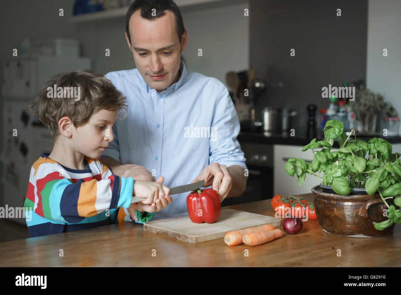 Padre figlio di insegnamento per tagliare le verdure in cucina Foto Stock