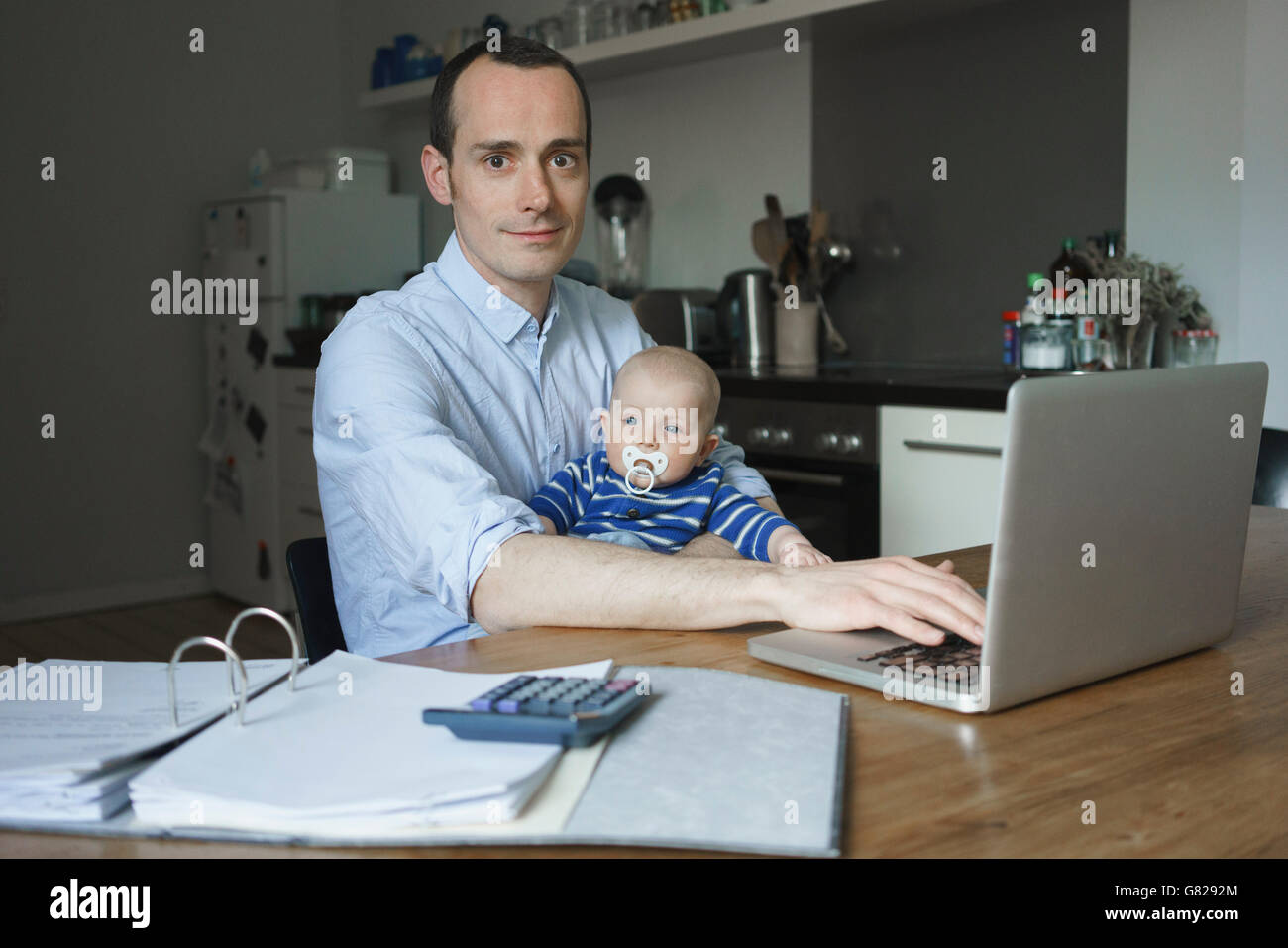Ritratto di Padre utilizzando laptop mentre si trasporta il figlio a casa Foto Stock