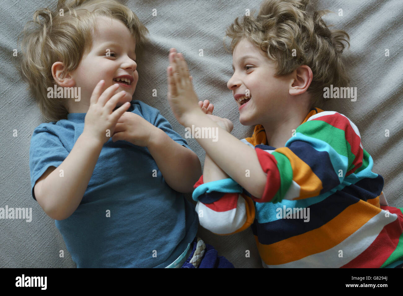 Angolo di alta vista dei fratelli felici giocando su letto di casa Foto Stock