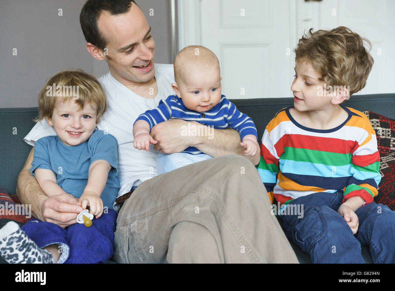 Vista frontale della famiglia felice seduto sul divano di casa Foto Stock