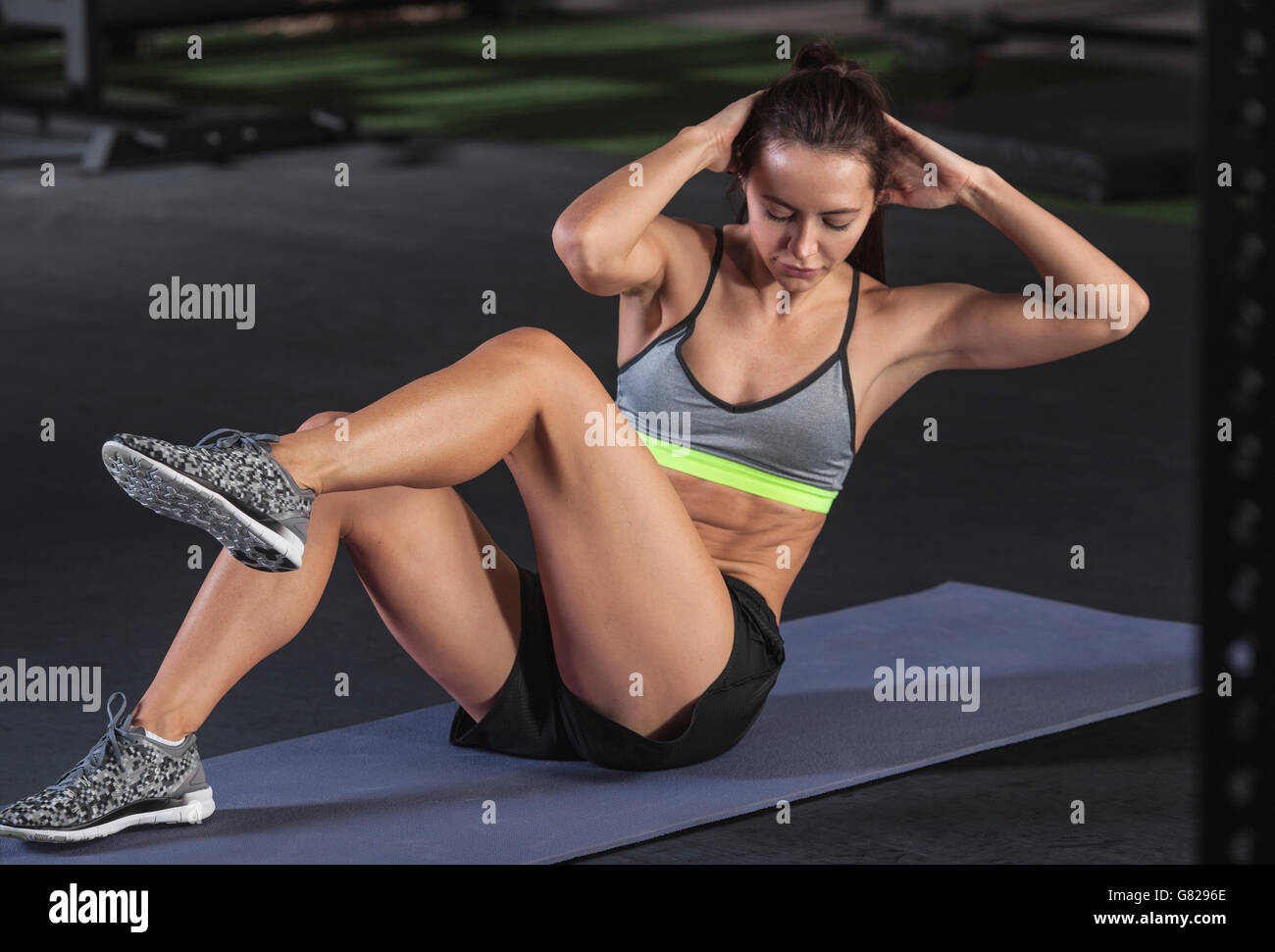 Giovane donna facendo sit ups sul tappeto di esercizio in palestra Foto Stock