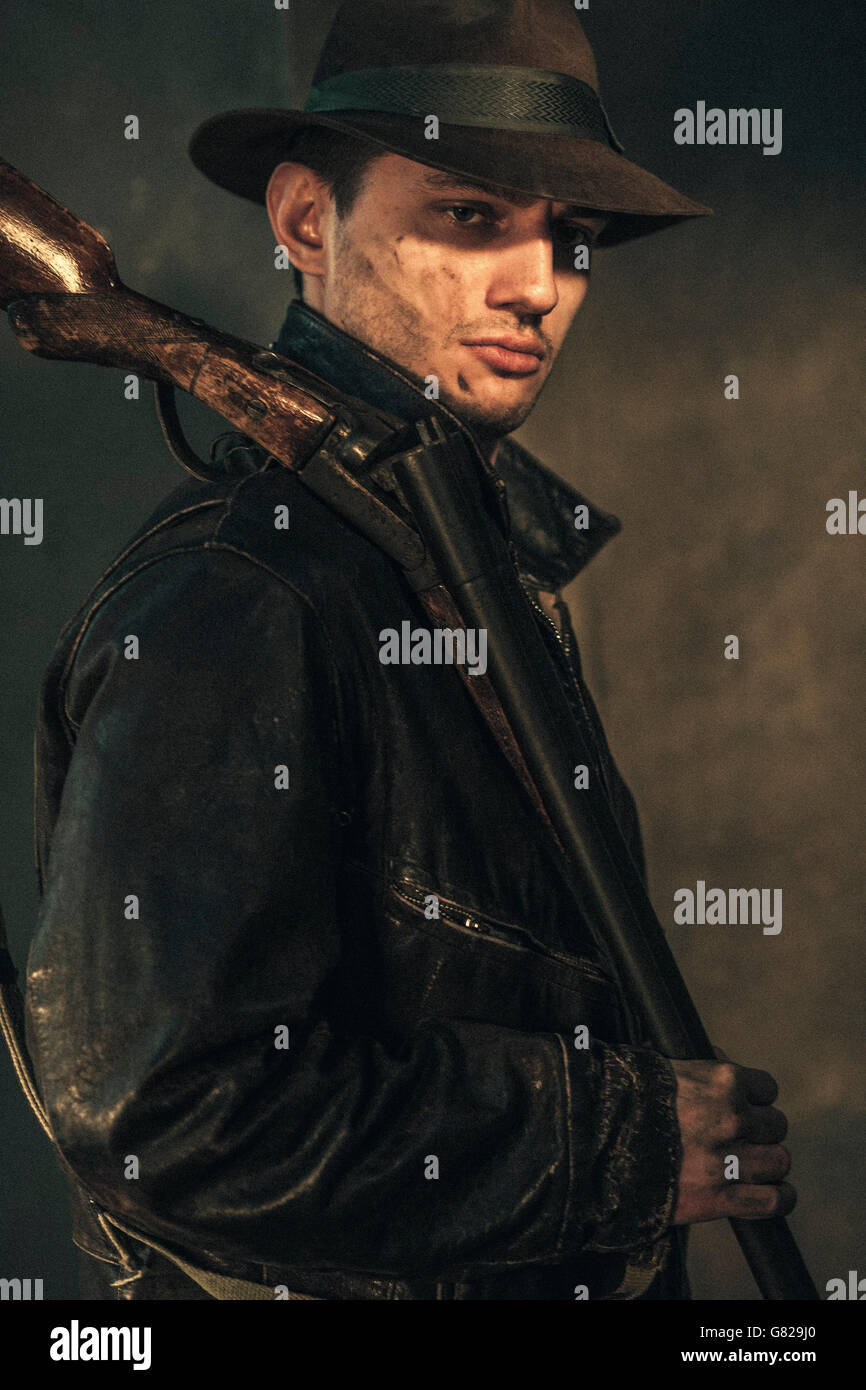 Fiducioso cowboy holding fucile su sfondo grigio Foto Stock