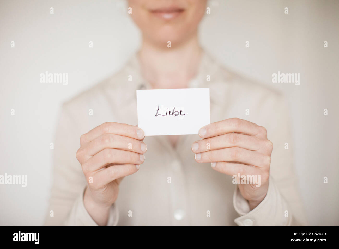 Sezione mediana della metà donna adulta tenendo premuto segno di amore a casa Foto Stock