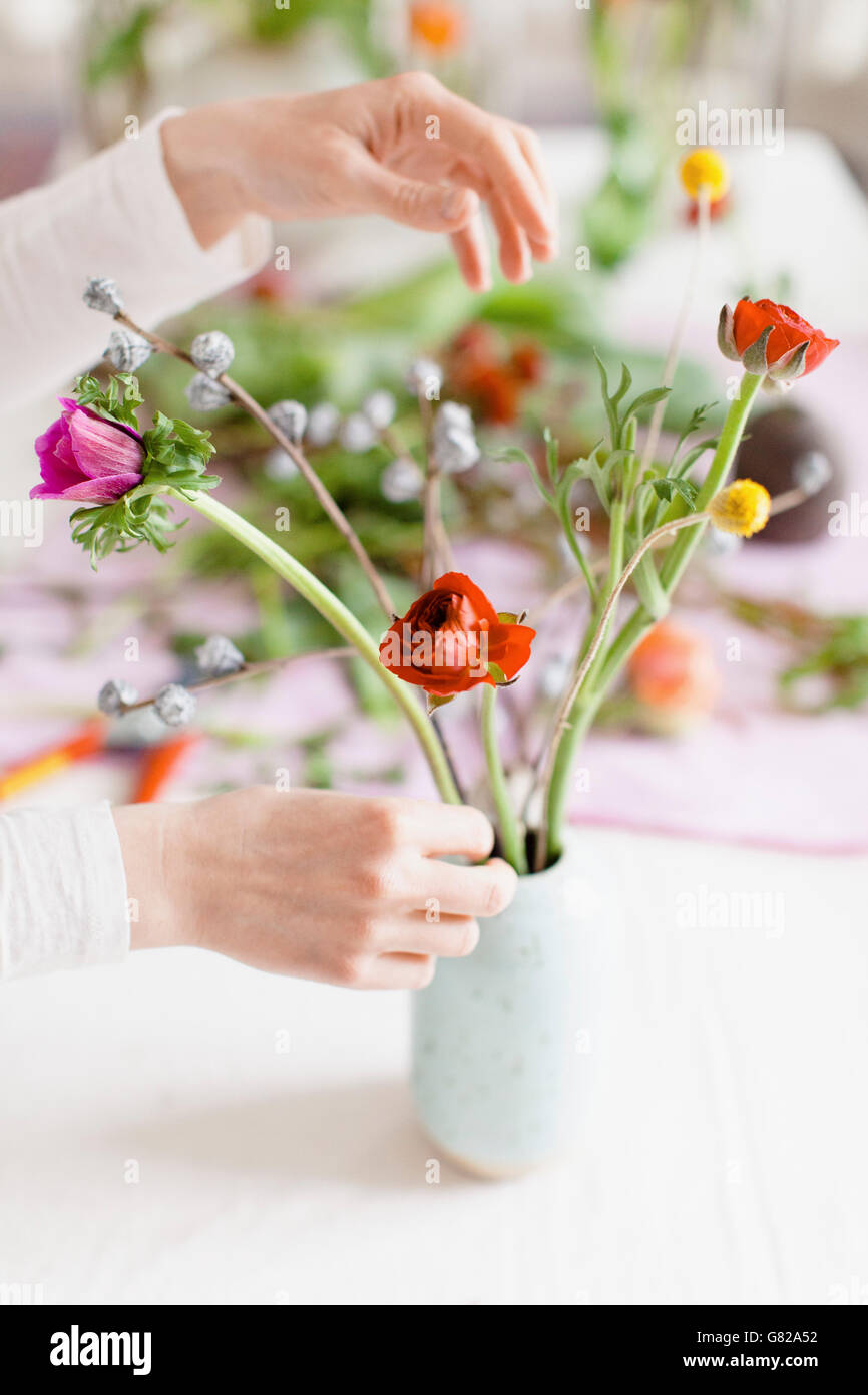 Immagine ritagliata della donna disponendo dei fiori in vaso sul tavolo a casa Foto Stock