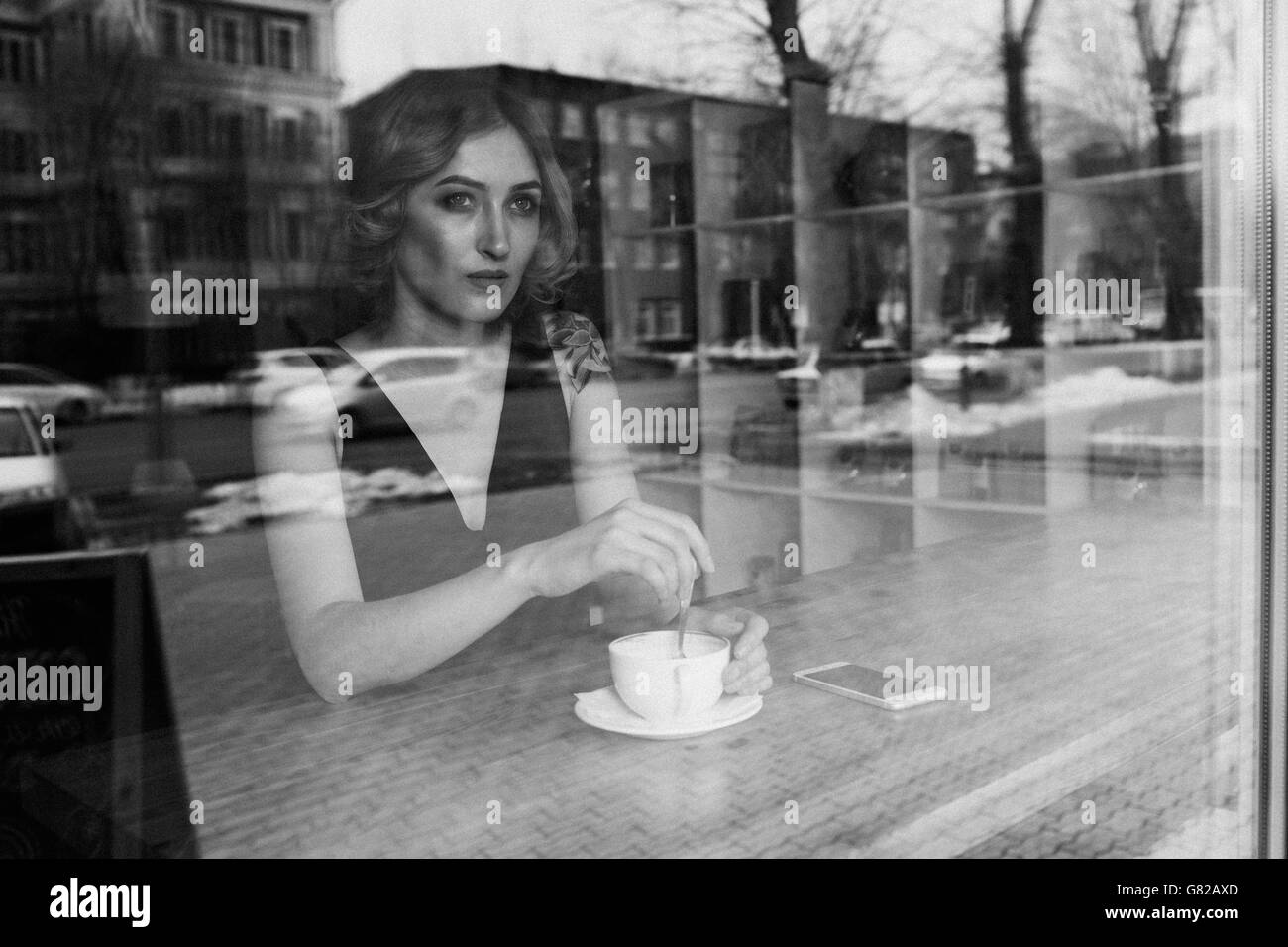 Considerato giovane donna agitazione caffè nella caffetteria Foto Stock