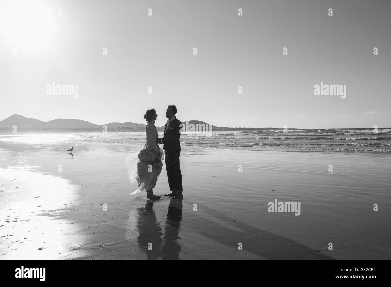 Lunghezza piena vista laterale di amare la sposa e lo sposo in piedi in spiaggia Foto Stock