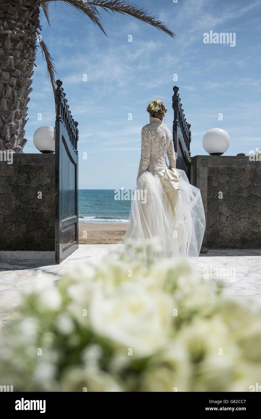 Vista posteriore della sposa passeggiate verso la spiaggia Foto Stock