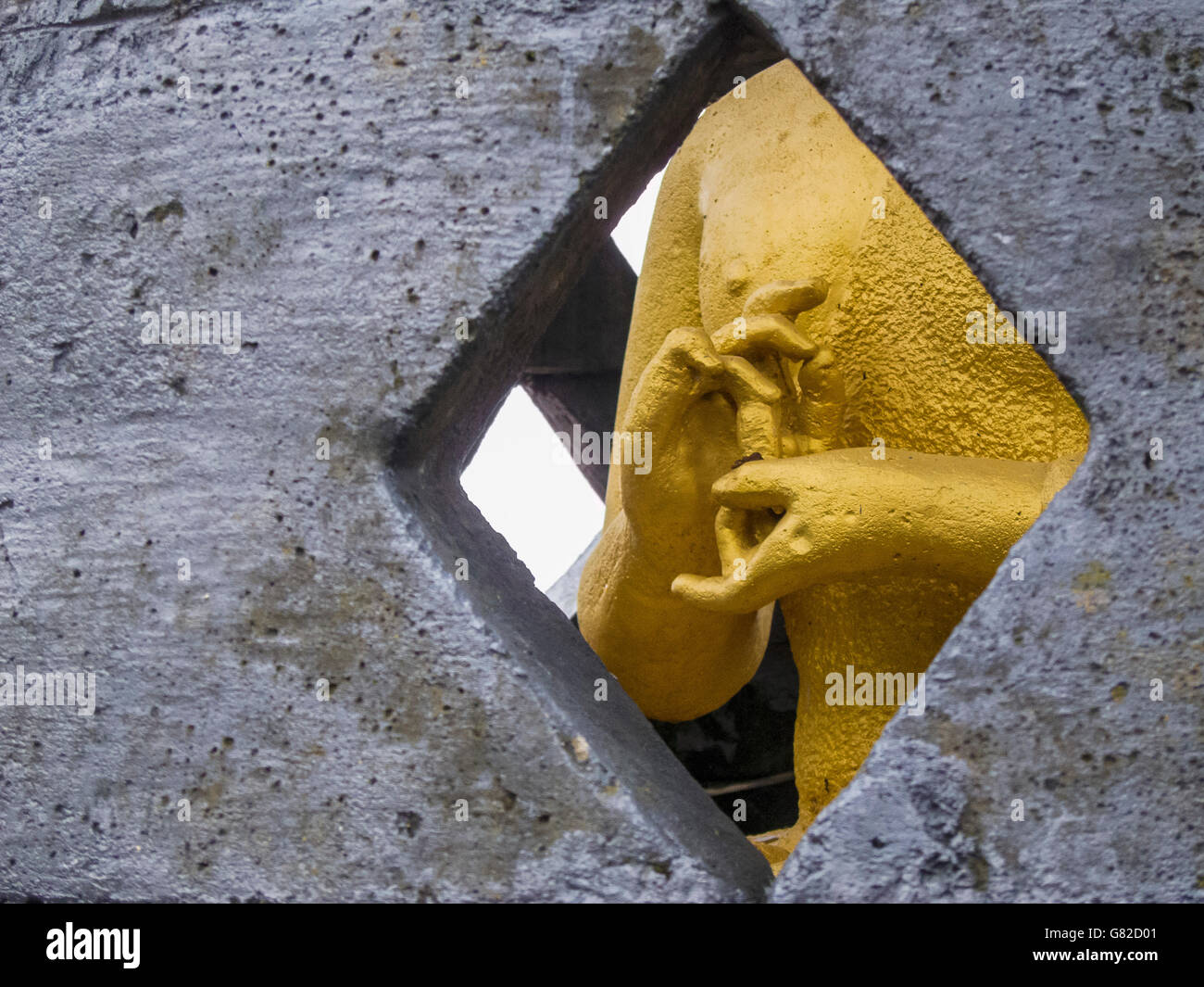 Statua dorata visto attraverso la forma a diamante finestra Foto Stock