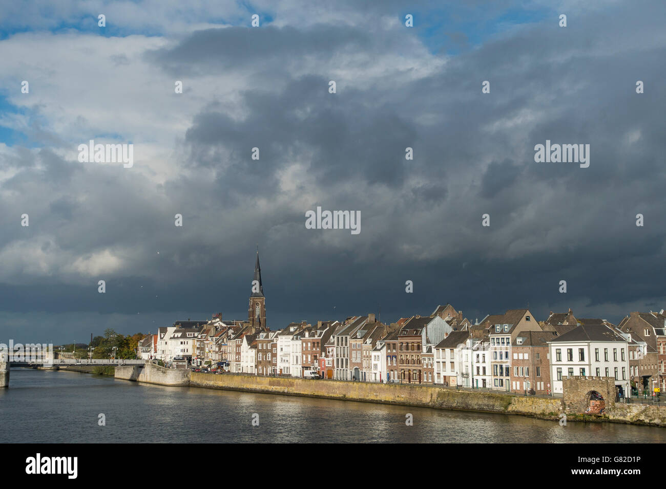 Il fiume Mosa da case in città contro il cielo nuvoloso Foto Stock