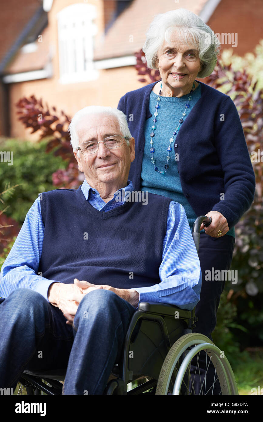 Senior uomo in carrozzella essendo spinto dalla moglie Foto Stock