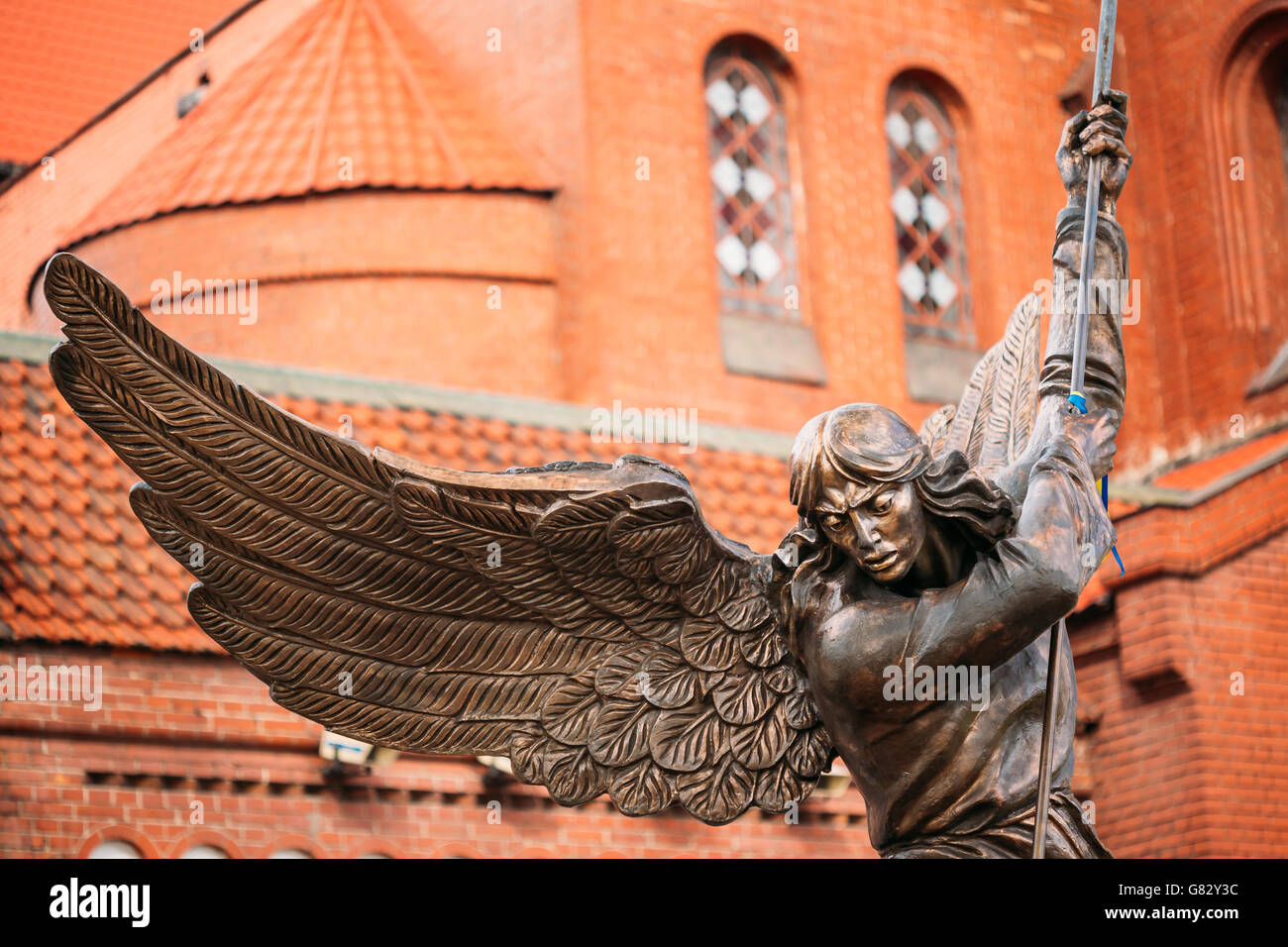 Statua di San Michele Arcangelo nei pressi di rosso la Chiesa cattolica di San Simone e Sant'Elena su piazza Indipendenza a Minsk, Bielorussia Foto Stock