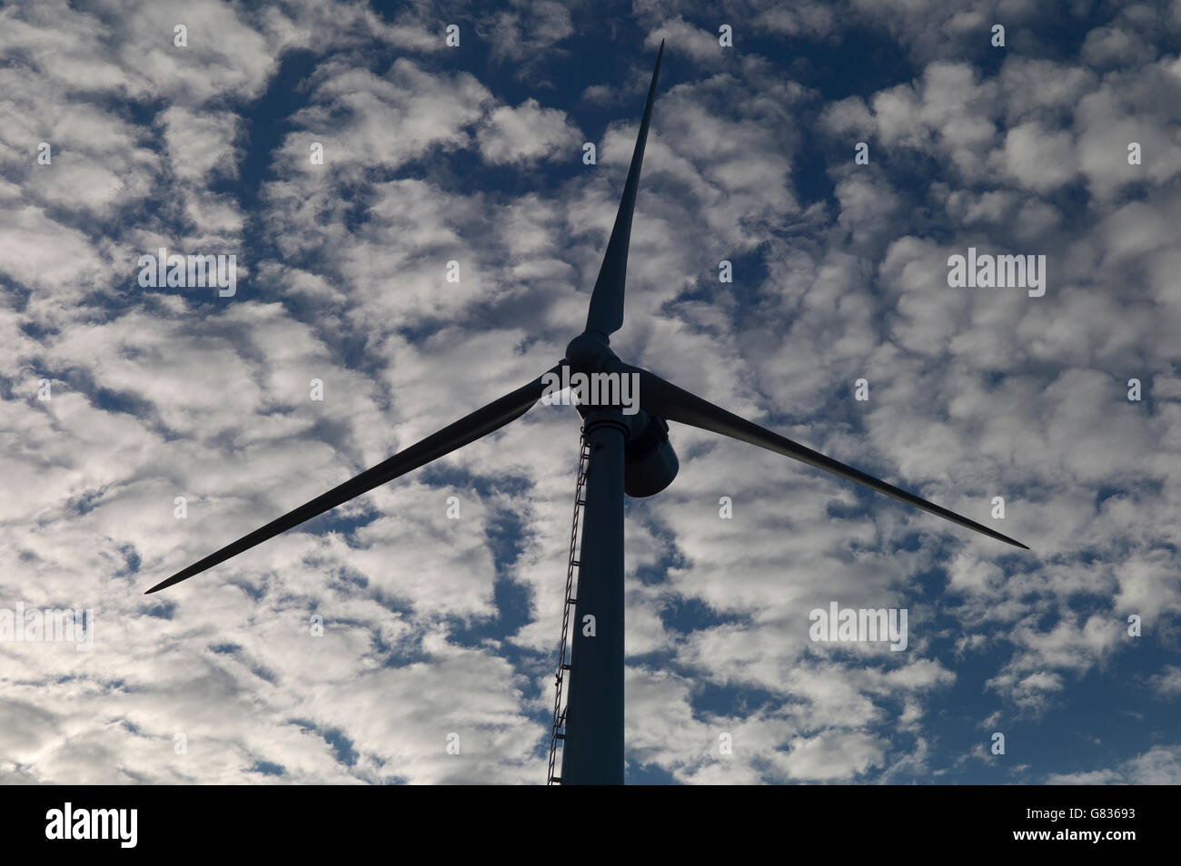 Turbina eolica in silhouette contro il cielo nuvoloso Foto Stock