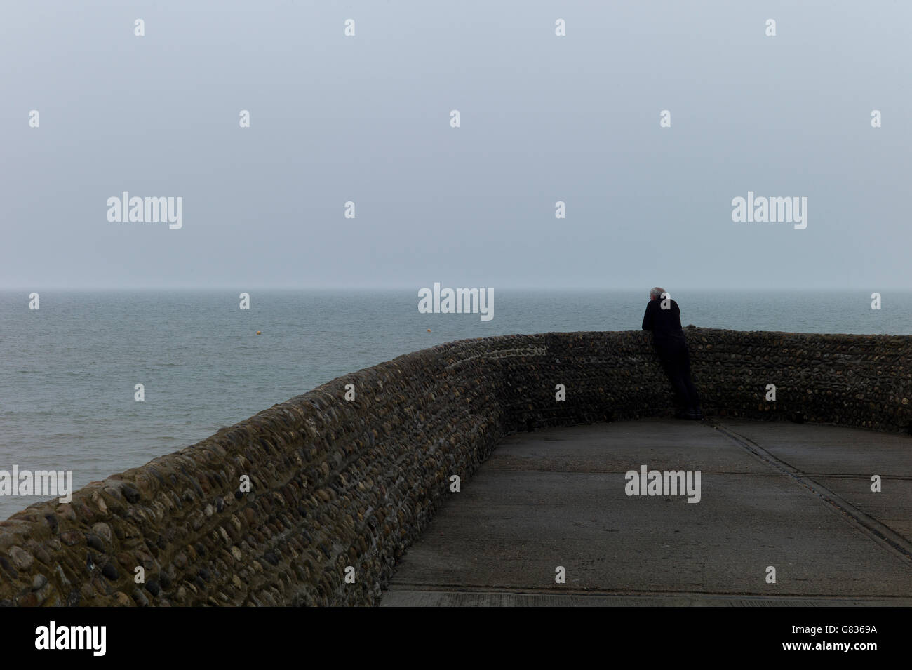 Lone figura con lo sguardo sul mare dalla pietra groyne, Brighton, Sussex Foto Stock