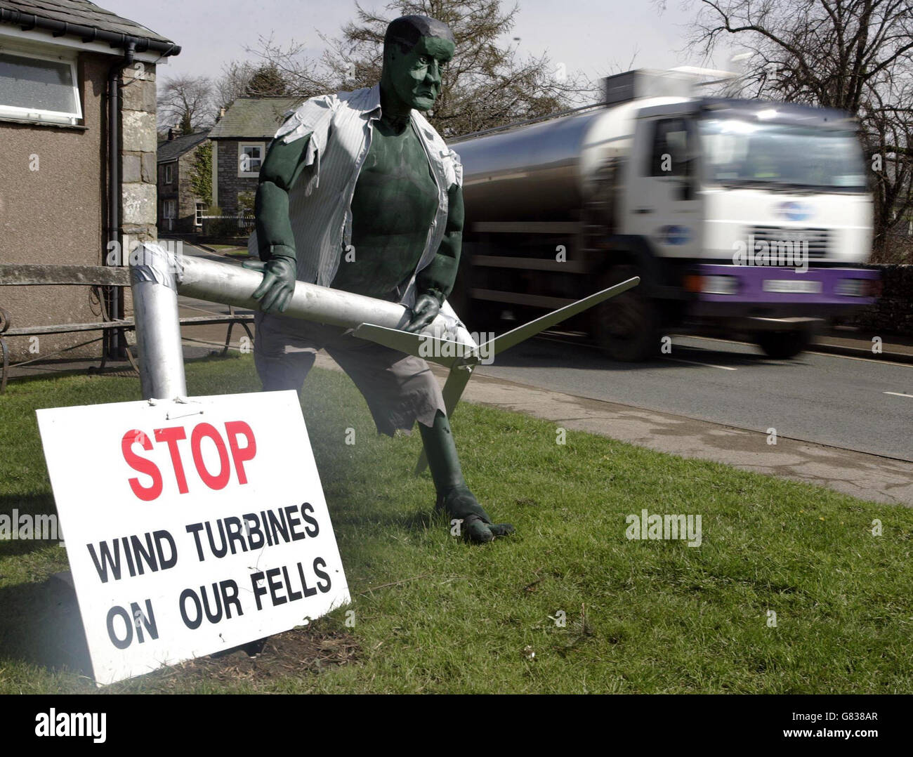 Una petroliera passa una caricatura dell'incredibile Hulk distruggendo una turbina eolica. Oggi è iniziata un'indagine sui piani per costruire la più grande fattoria eolica europea sul brughiera in Cumbria. Le proposte vedrebbero la costruzione di 27 turbine, ognuna in piedi 377 piedi di altezza, sulla terra a Whinash, a nord di Kendal. Foto Stock