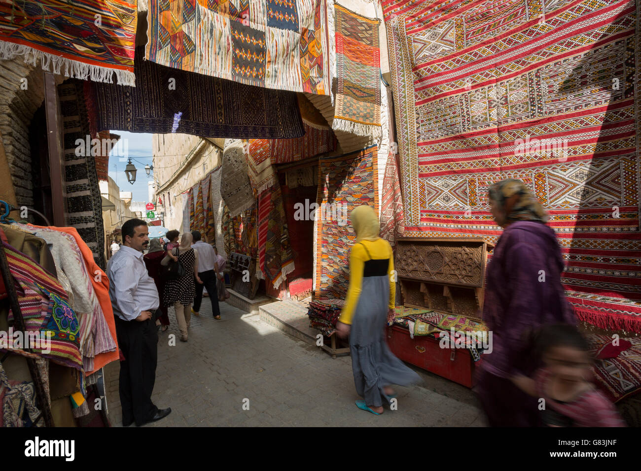 I residenti locali dash attraverso il tappeto rivestito di strette stradine della medina di Fez in Marocco. Foto Stock