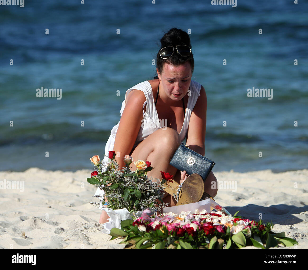 Una donna guarda i tributi floreali sulla spiaggia vicino all'hotel RIU Imperial Marhaba a Sousse, Tunisia, mentre i vacanzieri britannici sfidano i terroristi e continuano a rimanere a Sousse nonostante il bagno di sangue sulla spiaggia. PREMERE ASSOCIAZIONE foto. Data immagine: Martedì 30 giugno 2015. Le sabbie di Sousse erano tranquille e calme oggi, mentre turisti e gente del posto continuavano a rendere omaggio ai 38 morti fuori dagli hotel RIU Imperial Marhaba e Bellevue. I fiori continuano ad essere posati in tre memoriali a forma di cuore che segnano dove tante persone hanno perso la vita, con molte persone in lacrime come theyy Foto Stock