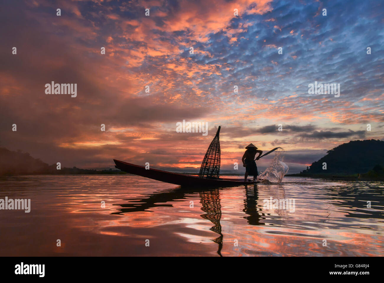 Uomo in piedi in barca da pesca al tramonto, il fiume Mekong, Thailandia Foto Stock