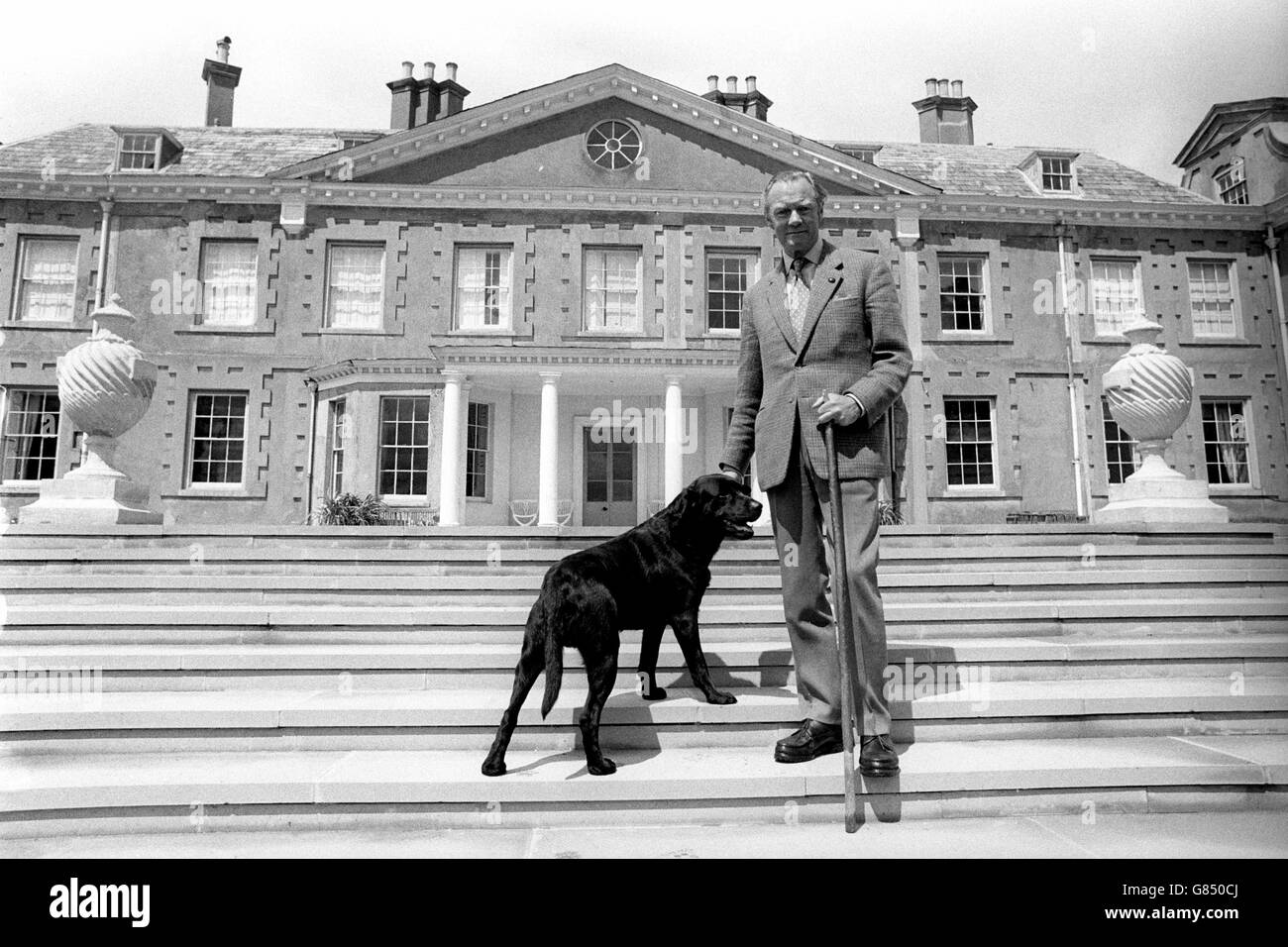 L'ottavo duca di Wellington, con il suo Labrador Brandy nero, sui gradini della sua residenza di campagna di famiglia del XVII secolo - Stratfield Saye House - vicino a Reading, Berkshire. E 'destinato ad essere aperto al pubblico per la prima volta quest'anno. Foto Stock