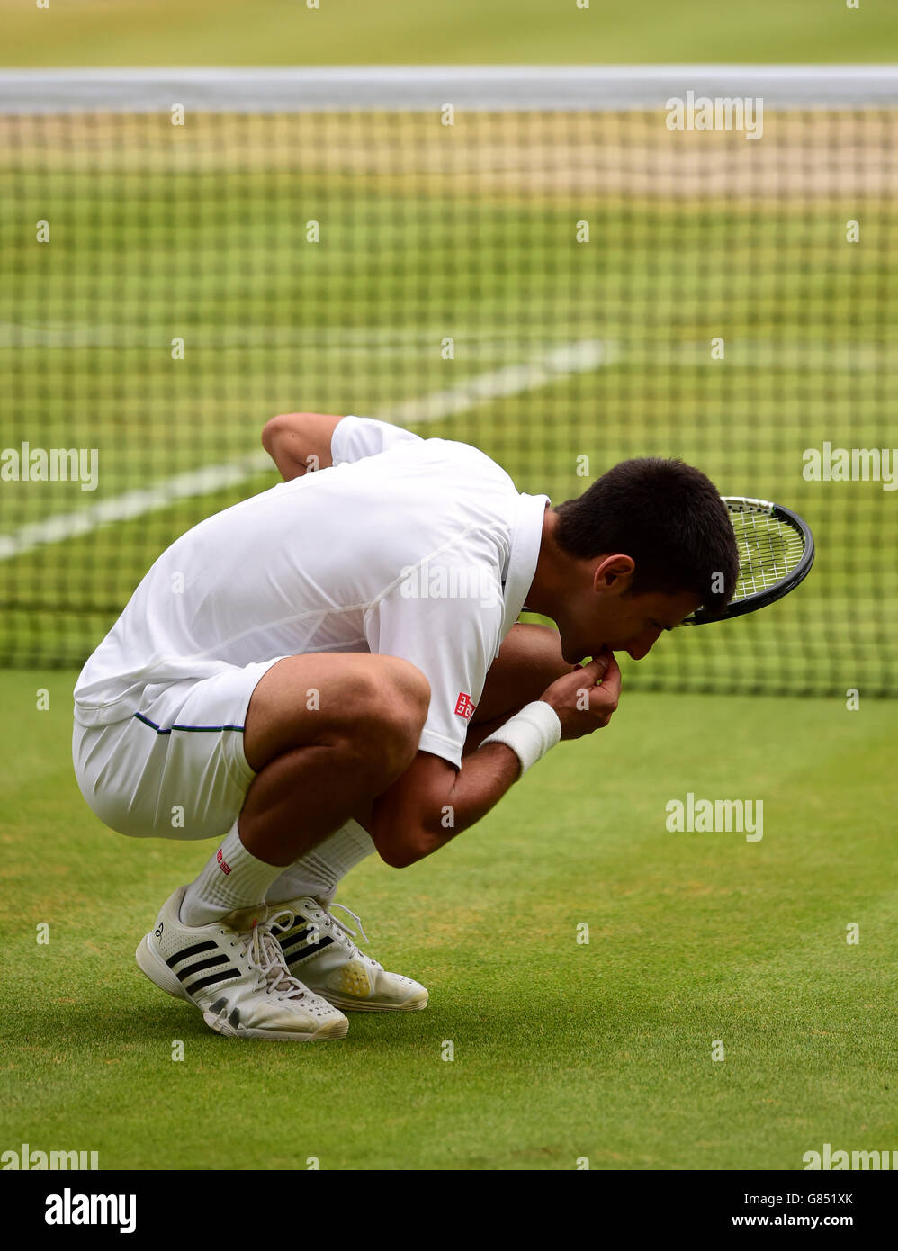 Novak Djokovic mangia l'erba fuori dal campo dopo aver battuto Roger Federer nella finale di Mens Singles il tredici giorno dei Campionati di Wimbledon all'All England Lawn Tennis and Croquet Club di Wimbledon. Foto Stock
