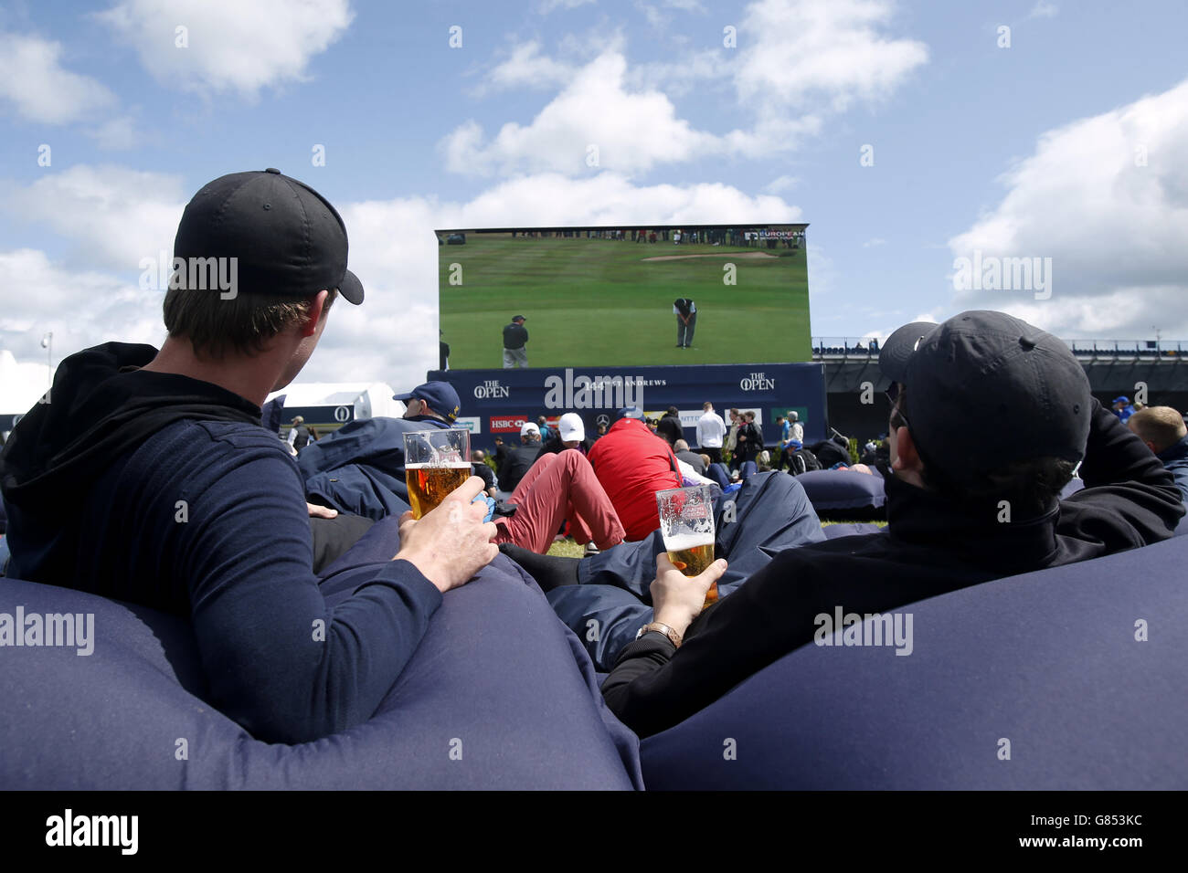 Gli appassionati di golf si rilassano su sacchi di fagioli giganti mentre i venti forti sospendono il gioco durante il terzo giorno dell'Open Championship 2015 a St Andrews, Fife. Foto Stock