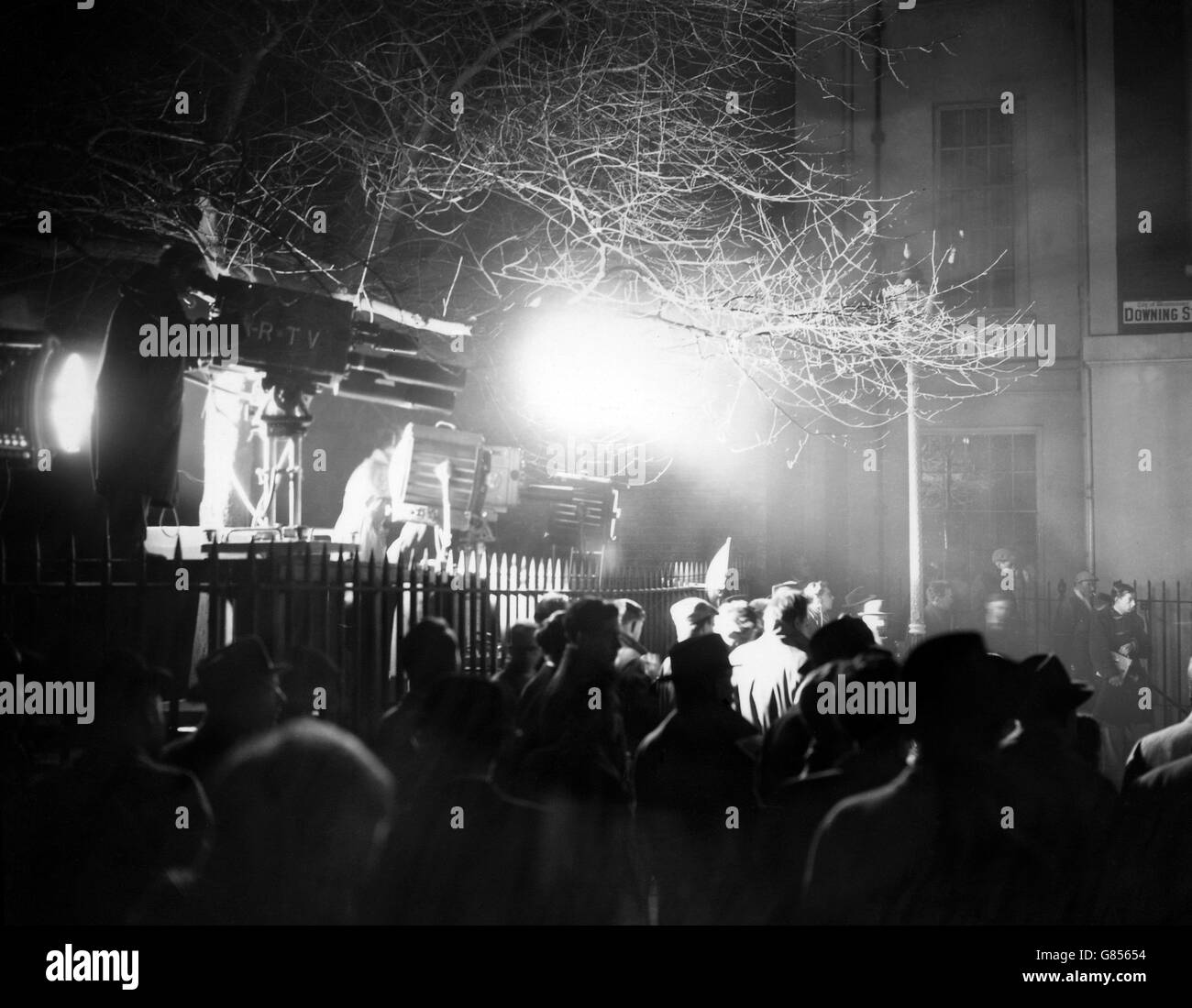 Le lampade di un'unità televisiva silhouette gli astanti nella Downing Street di Londra, come il nuovo primo ministro Harold Macmillan assume la guida del governo britannico. Foto Stock