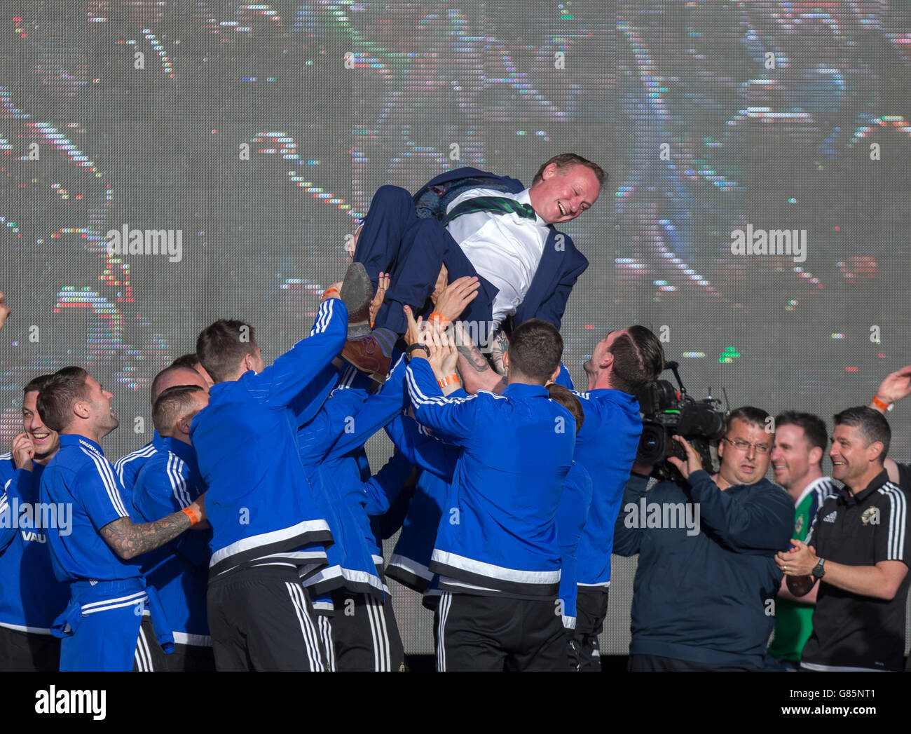 Irlanda del Nord i giocatori sollevare manager Michael O'Neill in aria come si celebra con i tifosi delle squadre successo nel 2016 Campionato Euro in Francia mentre al Titanic Fanzone, Belfast. Foto Stock