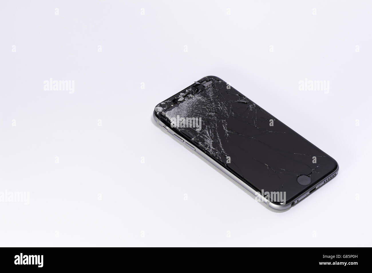 Un telefono cellulare con schermo rotto su sfondo bianco Foto Stock
