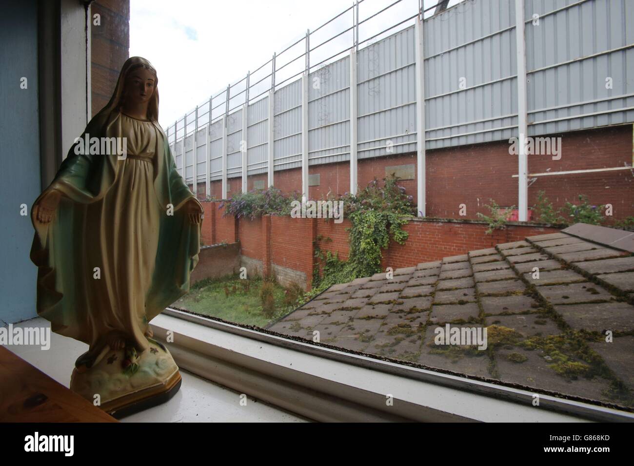 Una vista da una casa adiacente, una delle mura di pace più antiche di Belfast tra Finn Square sulla Falls Road e Boundary Street sulla Shankill Road. Foto Stock