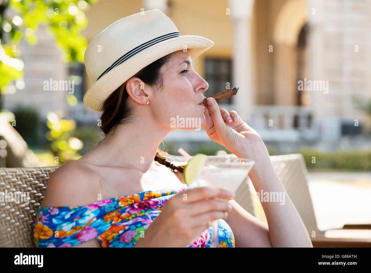 Una donna gustando un cocktail e un sigaro in un albergo a l'Avana, Cuba Foto Stock