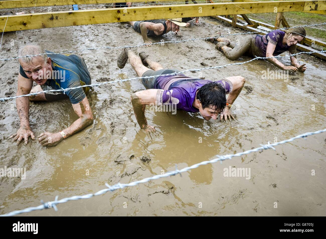 I partecipanti potranno sguazzare in fango scivoloso durante un evento di 12 km di percorso a ostacoli Tough Mudder a Cirencester, Wiltshire. Foto Stock