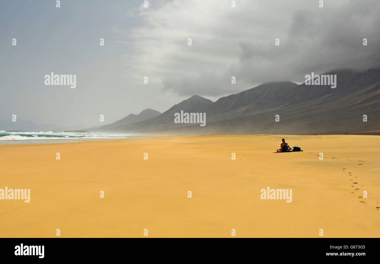 Uomo seduto sulla Spiaggia Cofete, Fuerteventura, Spagna Foto Stock