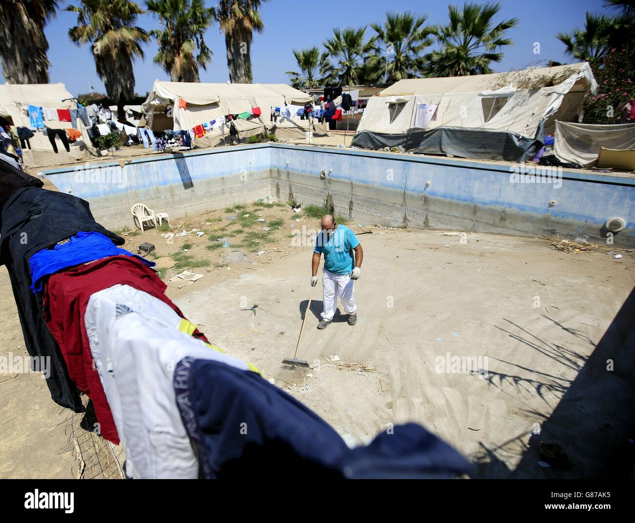 Un dipendente locale di Medecins Sans Frontieres elimina i rifiuti lasciati dai migranti in cerca di rifugio intorno all'area della piscina del delitto Capitano Elias Hotel a Kos Town, Kos, Grecia. Foto Stock