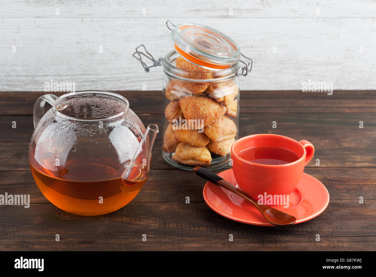 Cottage cheese biscotti dolci in un vasetto con tè nero in tazza e teiera. Profondità di campo. Foto Stock