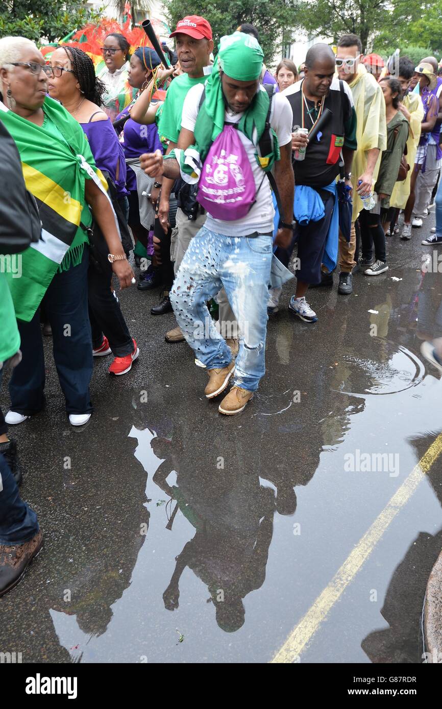 Le folle evitano una pozza d'acqua piovana mentre guardano la sfilata del Lunedi' di festa della Banca alla sfilata del Carnevale di Notting Hill 2015, nella parte ovest di Londra. Foto Stock