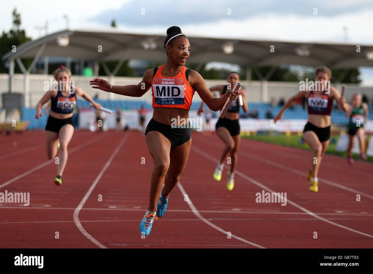 La squadra di relè delle ragazze delle Midlands dell'Inghilterra attraversa la fila per vincere l'evento delle ragazze 4 x 100 m ai Giochi scolastici 2015 di Sainsbury alla Manchester Regional Arena. Foto Stock