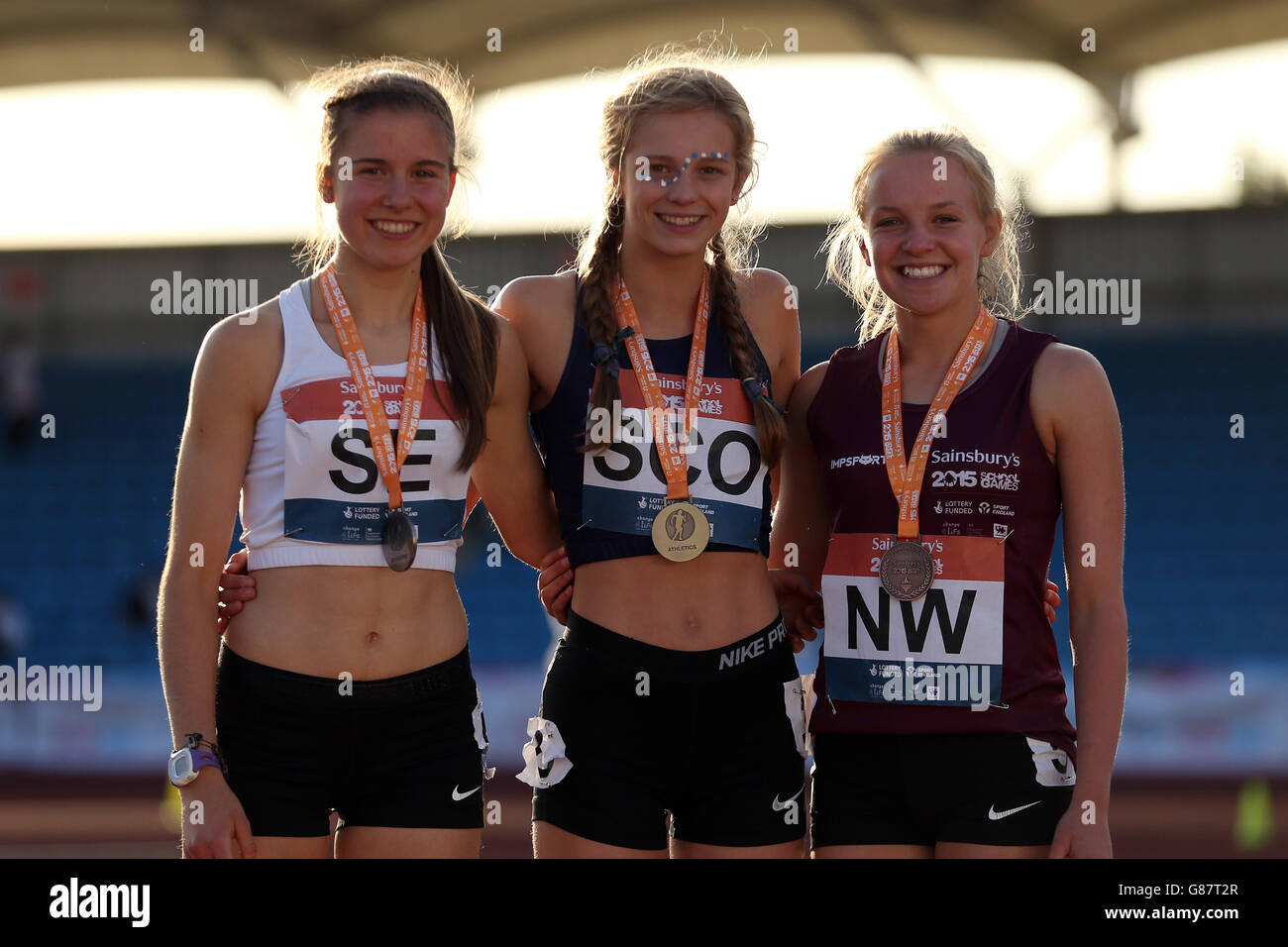 (l-r) Inghilterra Chloe Sharp del sud-est, Erin Wallace della Scozia e Katie Lowery dell'Inghilterra nord-ovest ricevono le loro medaglie di 1500 m di ragazze durante la cerimonia di medaglia ai Giochi scolastici di Sainsbury's 2015 alla Manchester Regional Arena. Foto Stock