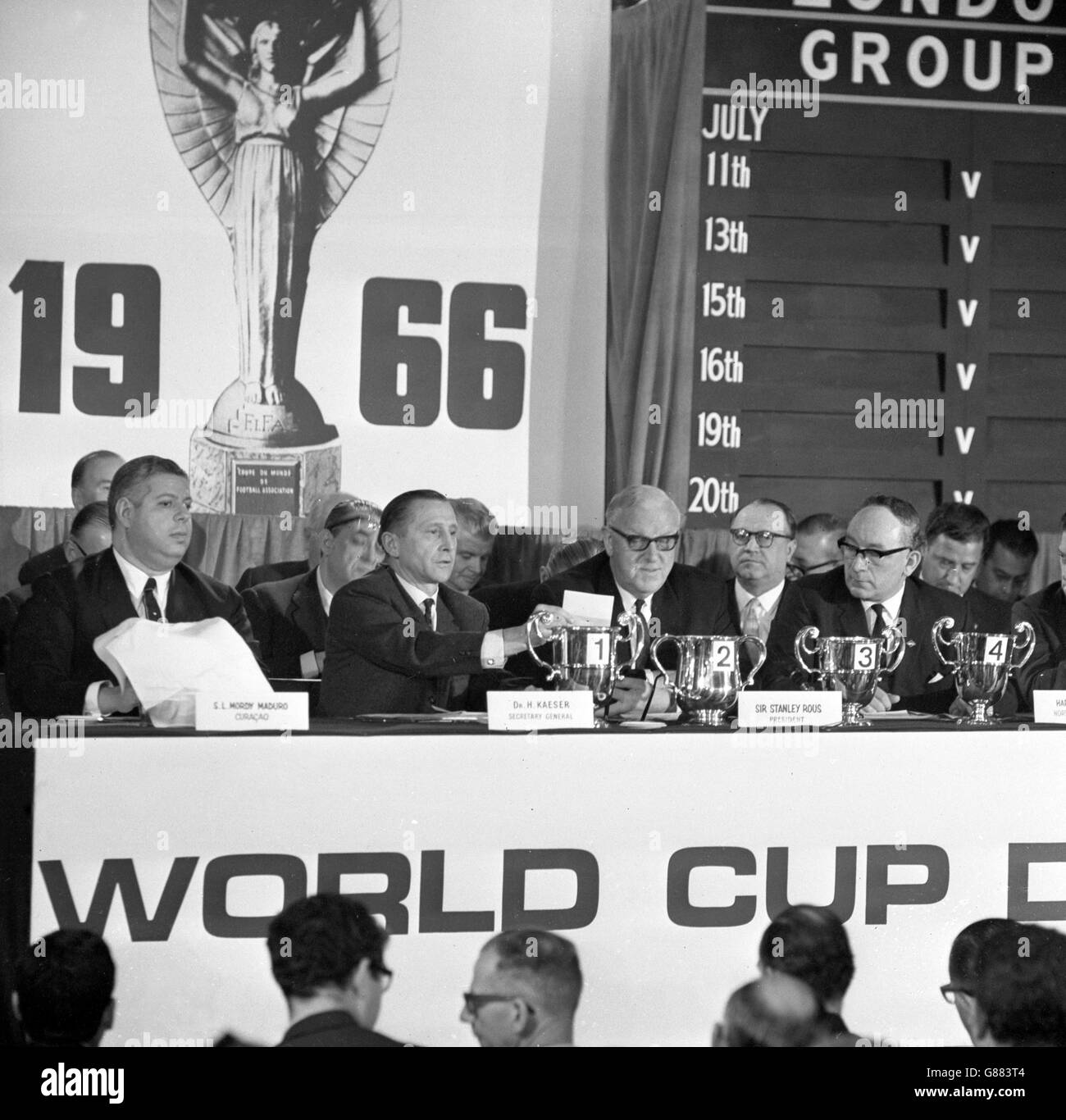 Il sorteggio per la Coppa del mondo viene effettuato presso il Royal Garden Hotel di Kensington. Il signor SL Mordy Maduro (a sinistra), membro Curacao del Comitato organizzatore della Coppa del mondo, è visto disegnare i documenti da una tazza coperta di asciugamani. Al tavolo ci sono anche Helmut Kaeser, Segretario Generale della FIFA, Sir Stanley Rous, Presidente della FIFA, Harry H Cavan, Membro del Comitato Organizzatore dell'Irlanda del Nord, e del conte di Harewood. Foto Stock