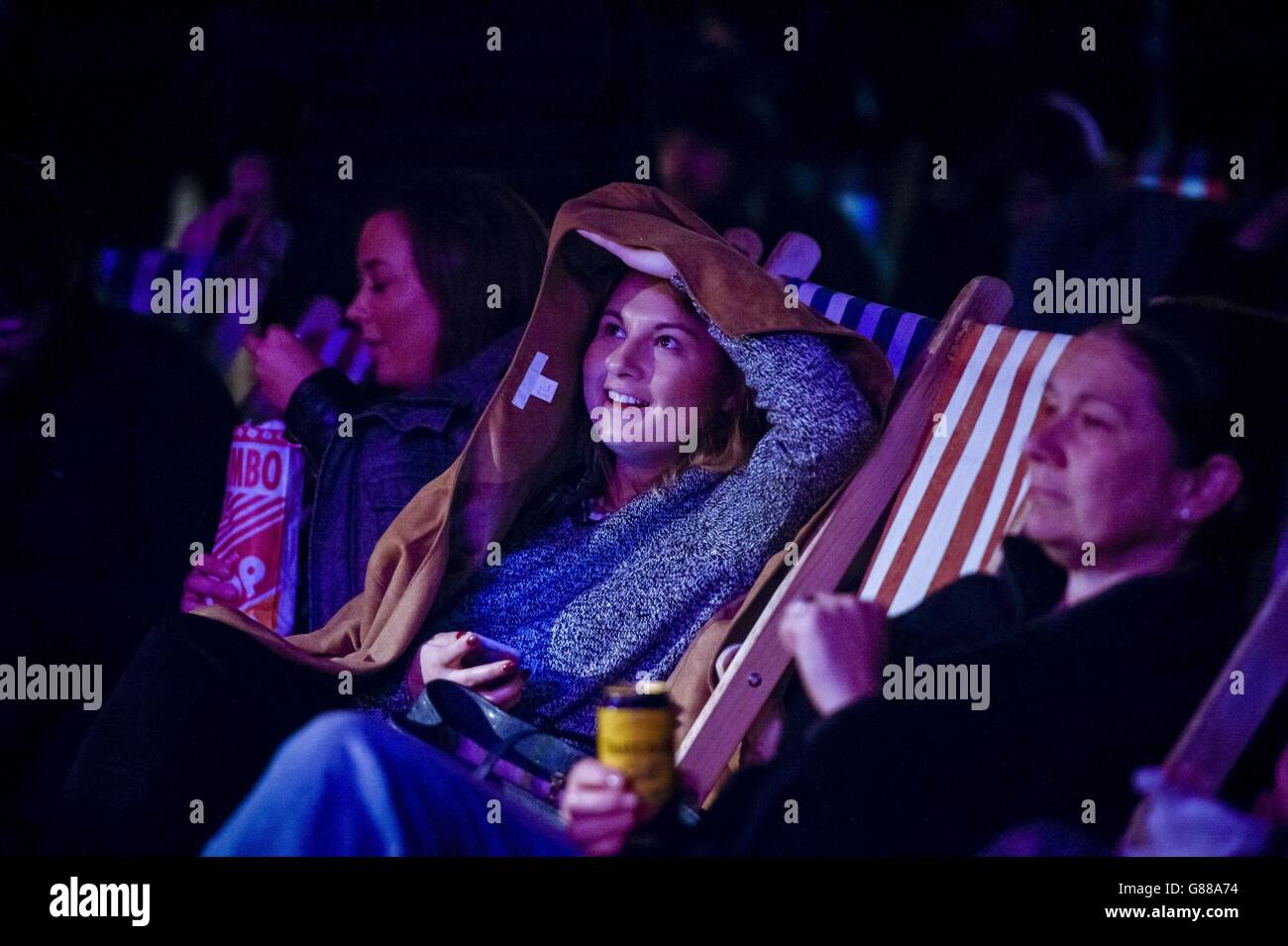 La gente nella folla guarda una serata di commedia al parco a tema Banksy's Dismaland a Weston-super-Mare. Foto Stock