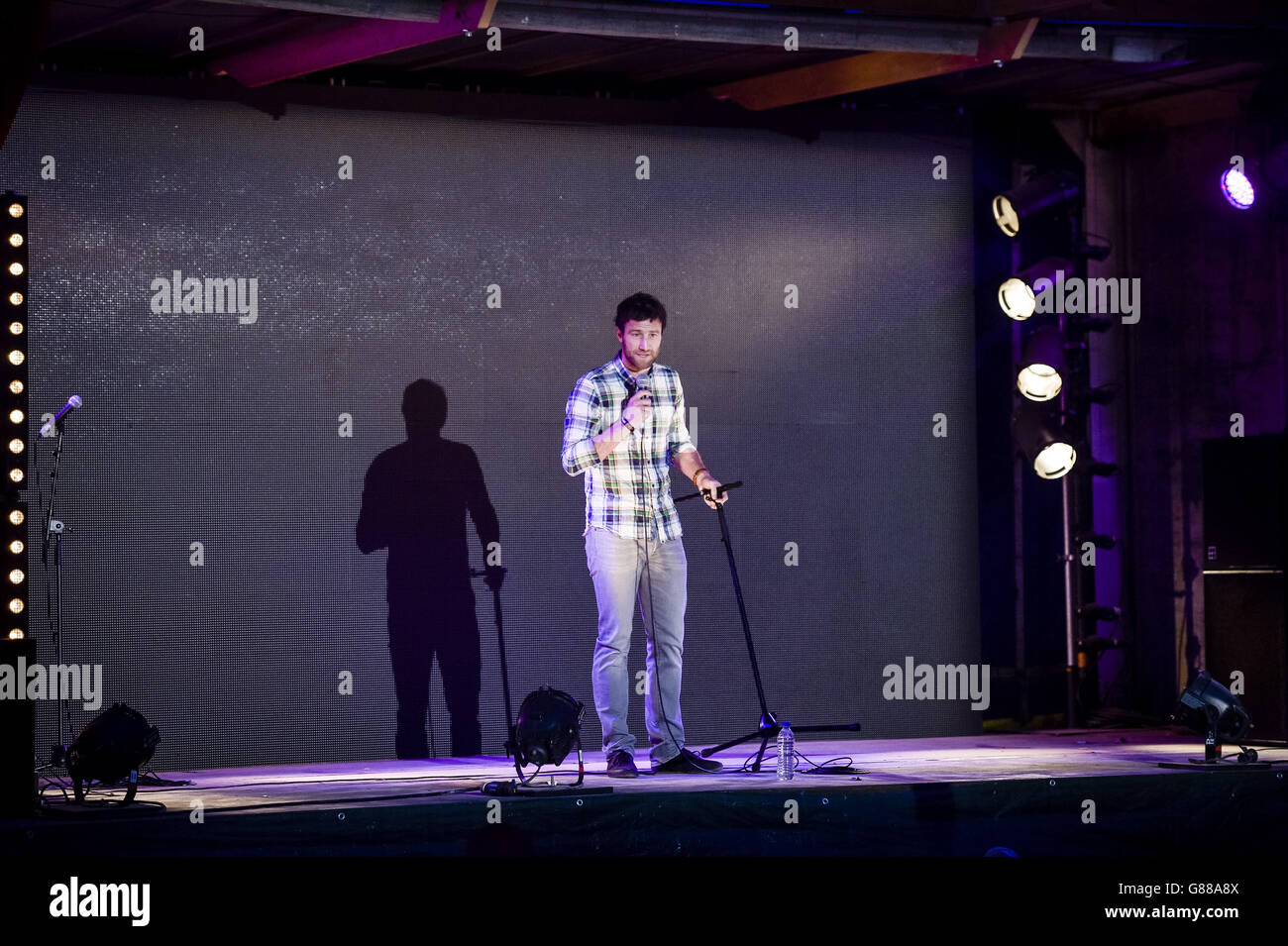 Il comico Andrew Bird suona durante una serata di commedia al parco a tema Banksy's Dismaland di Weston-super-Mare. Foto Stock