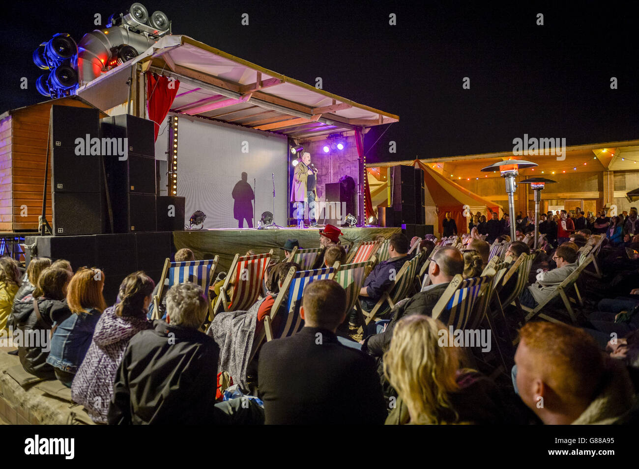 La folla guarda Mick Ferry esibirsi durante una serata di commedia al parco a tema Banksy's Dismaland a Weston-super-Mare. Foto Stock