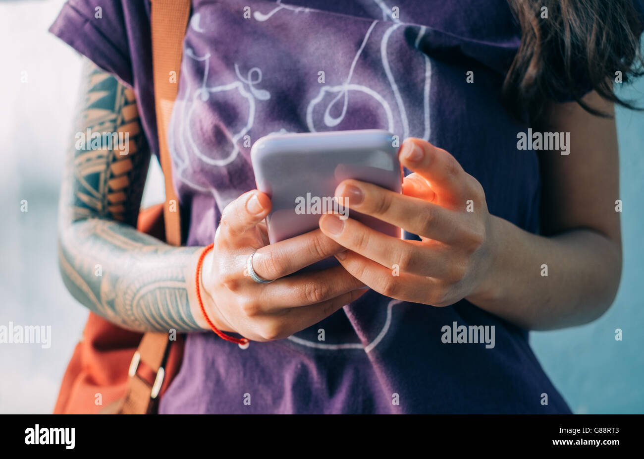 Donna con tatuaggi sms sul cellulare Foto Stock